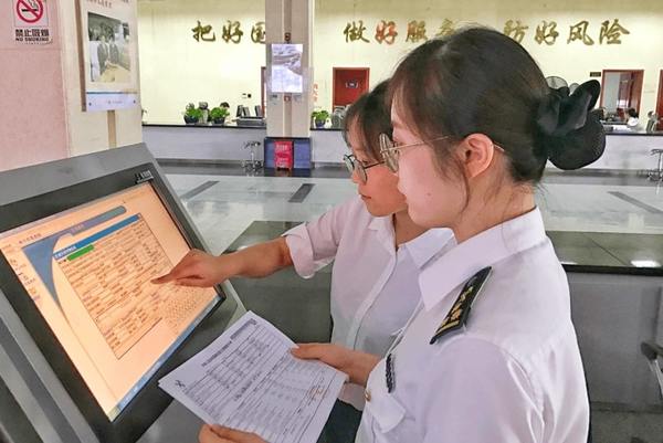 2 women in white uniform shirts working at computer screen in Chinese airport